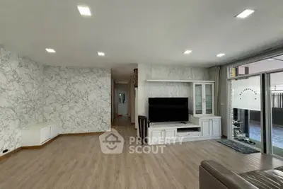 Spacious modern living room with elegant marble walls and large TV setup, perfect for family gatherings.