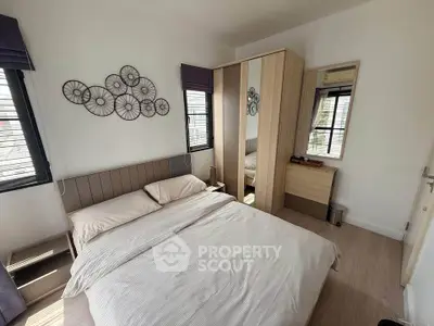 Cozy bedroom with modern decor and ample natural light, featuring a stylish bed and mirrored wardrobe.