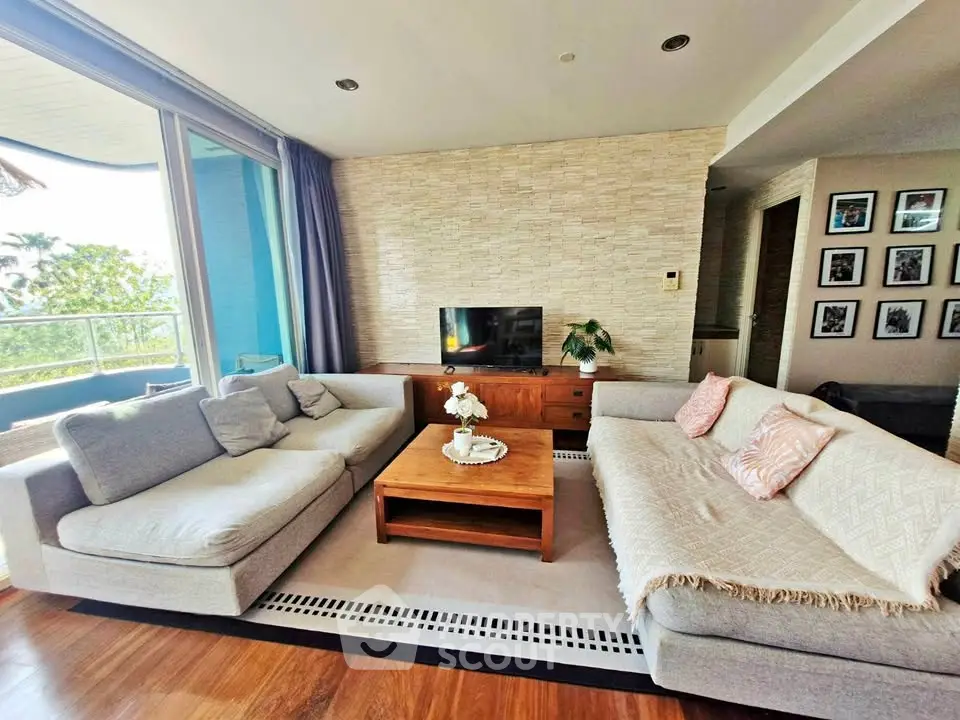 Spacious living room with modern decor and large windows offering natural light and scenic views.