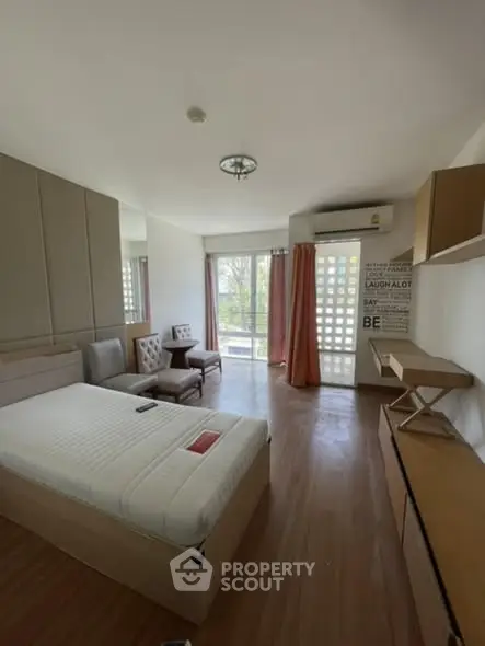 Spacious bedroom with modern decor and large window offering natural light.