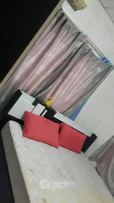 Cozy bedroom with modern decor and vibrant red pillows for a comfortable living experience.
