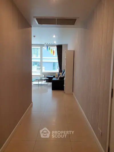 Modern apartment hallway leading to a cozy living room with large windows and stylish decor.