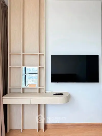Modern living room with sleek TV setup and stylish wooden shelving unit.