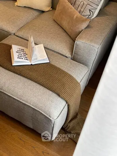 Cozy living room with stylish gray sofa and open book on ottoman, perfect for relaxation.
