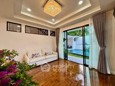 Elegant living room with pool view, featuring parquet flooring and modern lighting, perfect for relaxation.