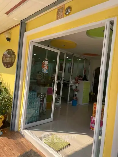 Charming storefront entrance with glass doors and vibrant yellow facade, inviting ambiance for potential customers.