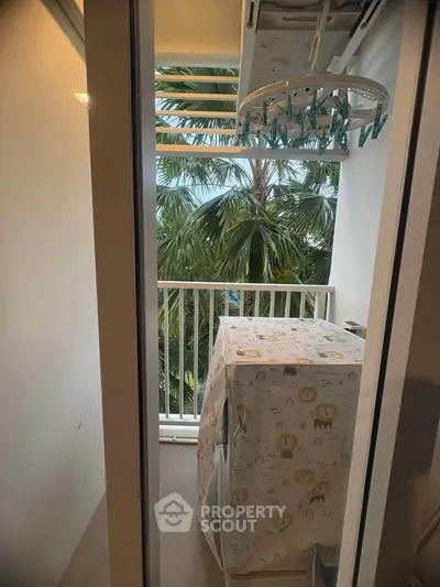 Cozy balcony with laundry area and lush greenery view, perfect for urban living.