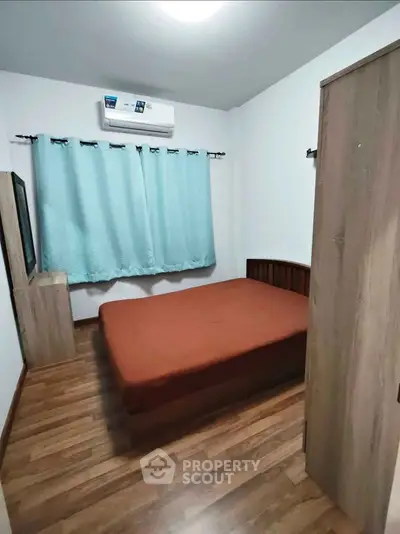 Cozy bedroom with wooden flooring and air conditioning in modern apartment.