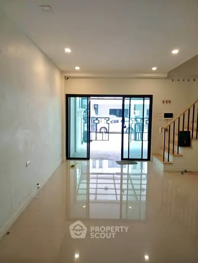Spacious modern living room with glossy floors and sliding glass doors opening to a balcony.