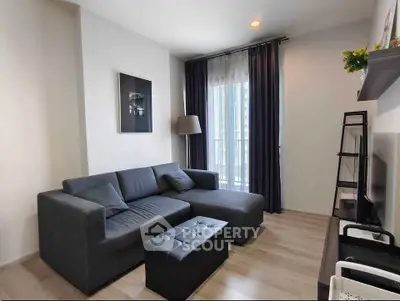 Modern living room with stylish gray sofa and natural light from large window.