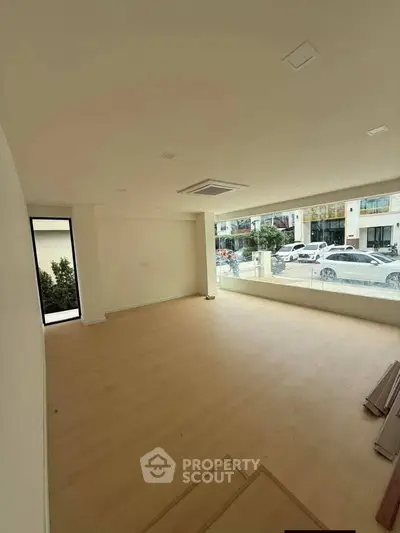 Spacious unfurnished room with large windows and street view, ideal for customization.
