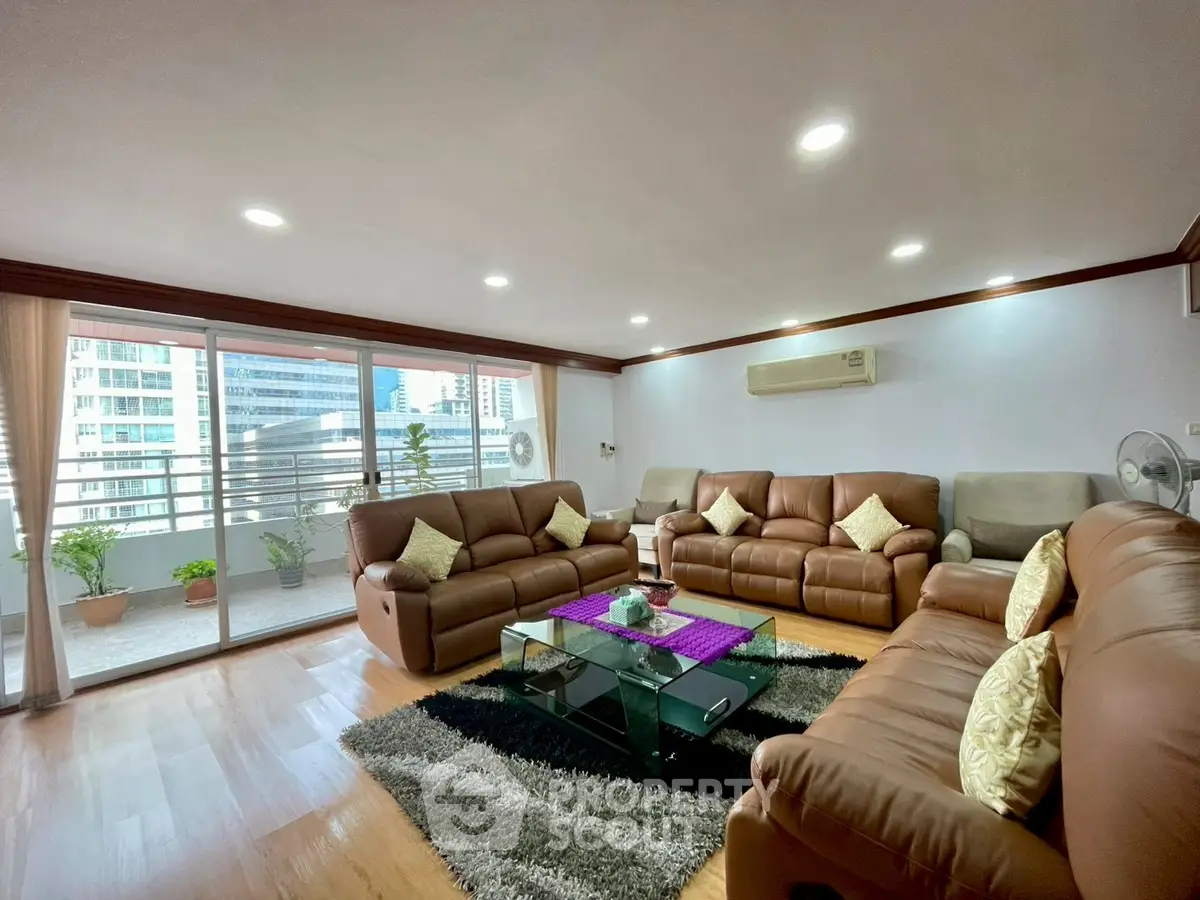 Spacious living room with leather sofas and city view balcony in modern apartment