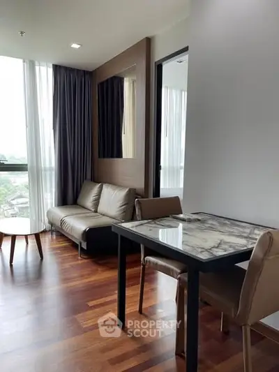 Modern living room with elegant marble table and cozy seating area, featuring large windows with natural light.