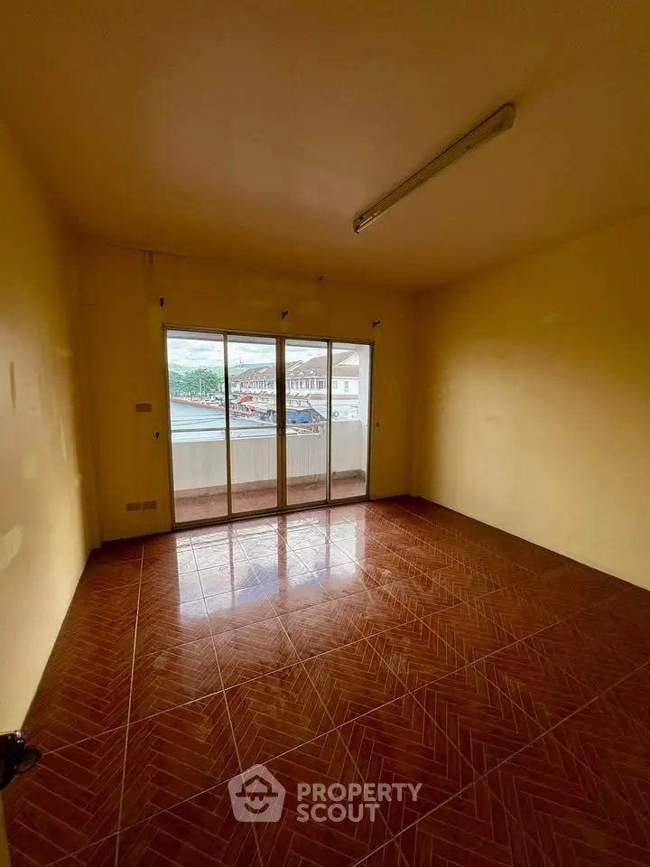 Spacious empty room with tiled floor and large sliding glass doors leading to a balcony.