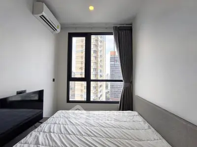 Modern bedroom with large window offering city view, featuring air conditioning and minimalist design.