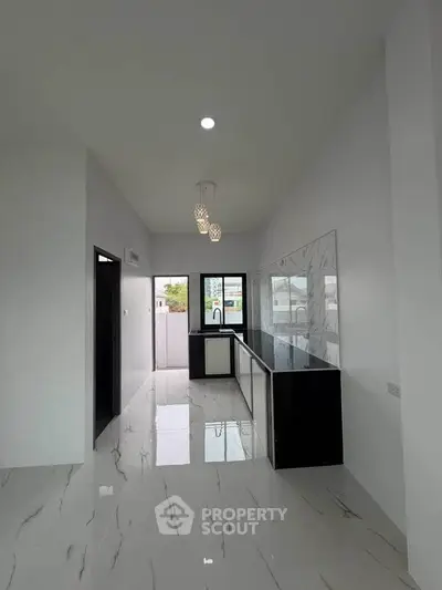 Modern kitchen with sleek black countertops and elegant pendant lighting in a spacious open layout.