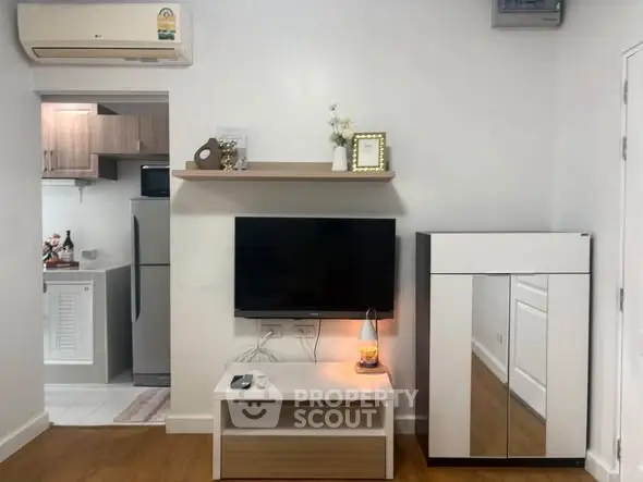 Modern living room with sleek TV setup and view into stylish kitchen