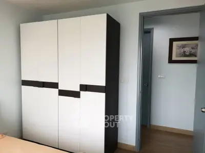 Modern bedroom with sleek wardrobe and wooden flooring, showcasing minimalist design and ample storage space.