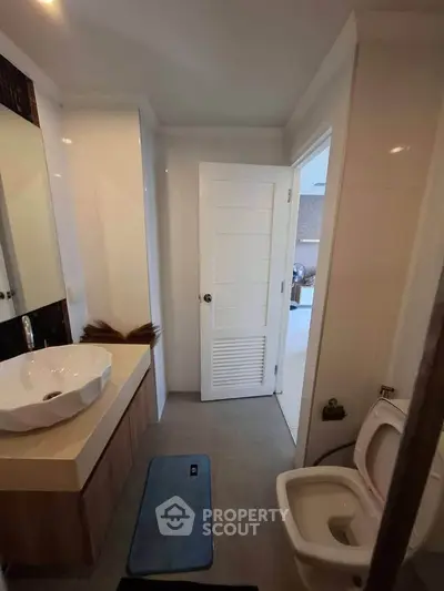 Modern bathroom with stylish sink and open door leading to bright room.