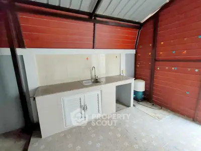 Charming outdoor kitchen with tiled countertop and red wooden walls, perfect for entertaining.