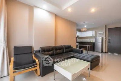 Modern living room with sleek black leather sofa and open kitchen layout