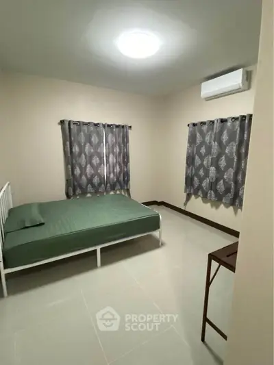 Spacious bedroom with modern decor and natural light, featuring a comfortable bed and air conditioning.