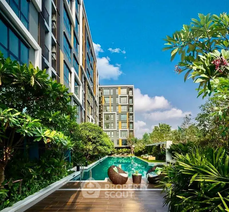 Luxurious modern apartment complex with lush greenery and inviting pool area.