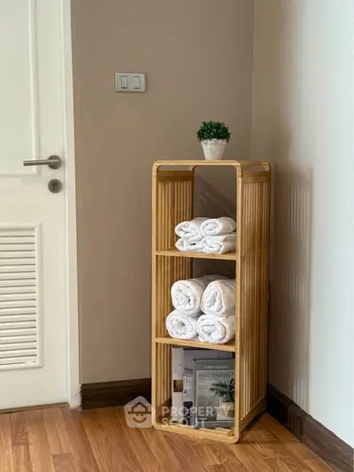 Stylish bathroom corner with wooden shelf and rolled towels for a cozy touch.
