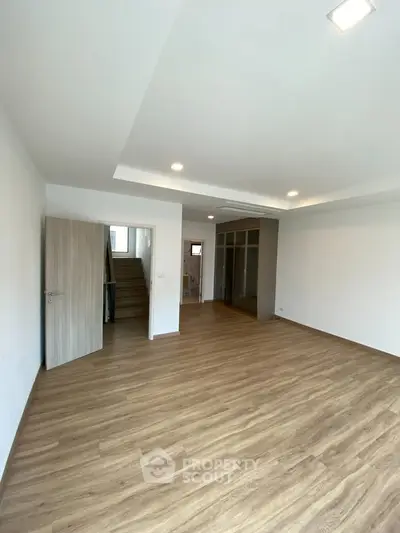 Spacious modern living room with wooden flooring and recessed lighting, perfect for family gatherings.