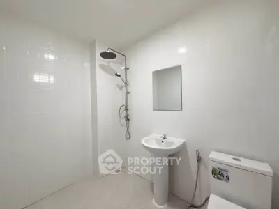 Modern minimalist bathroom with sleek white tiles and contemporary fixtures.