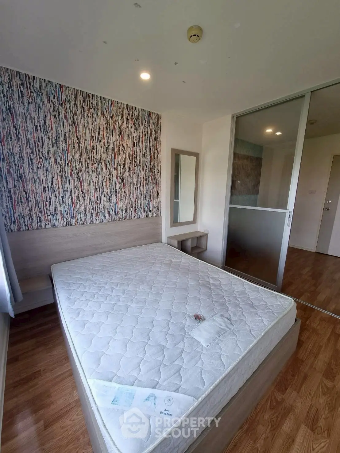 Modern bedroom with stylish wallpaper and wooden flooring in a contemporary apartment.