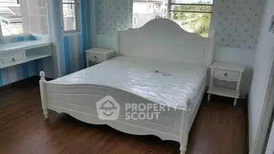 Charming bedroom with elegant white bed and scenic window views.