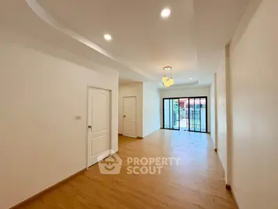 Spacious modern living room with wooden flooring and large windows for natural light.