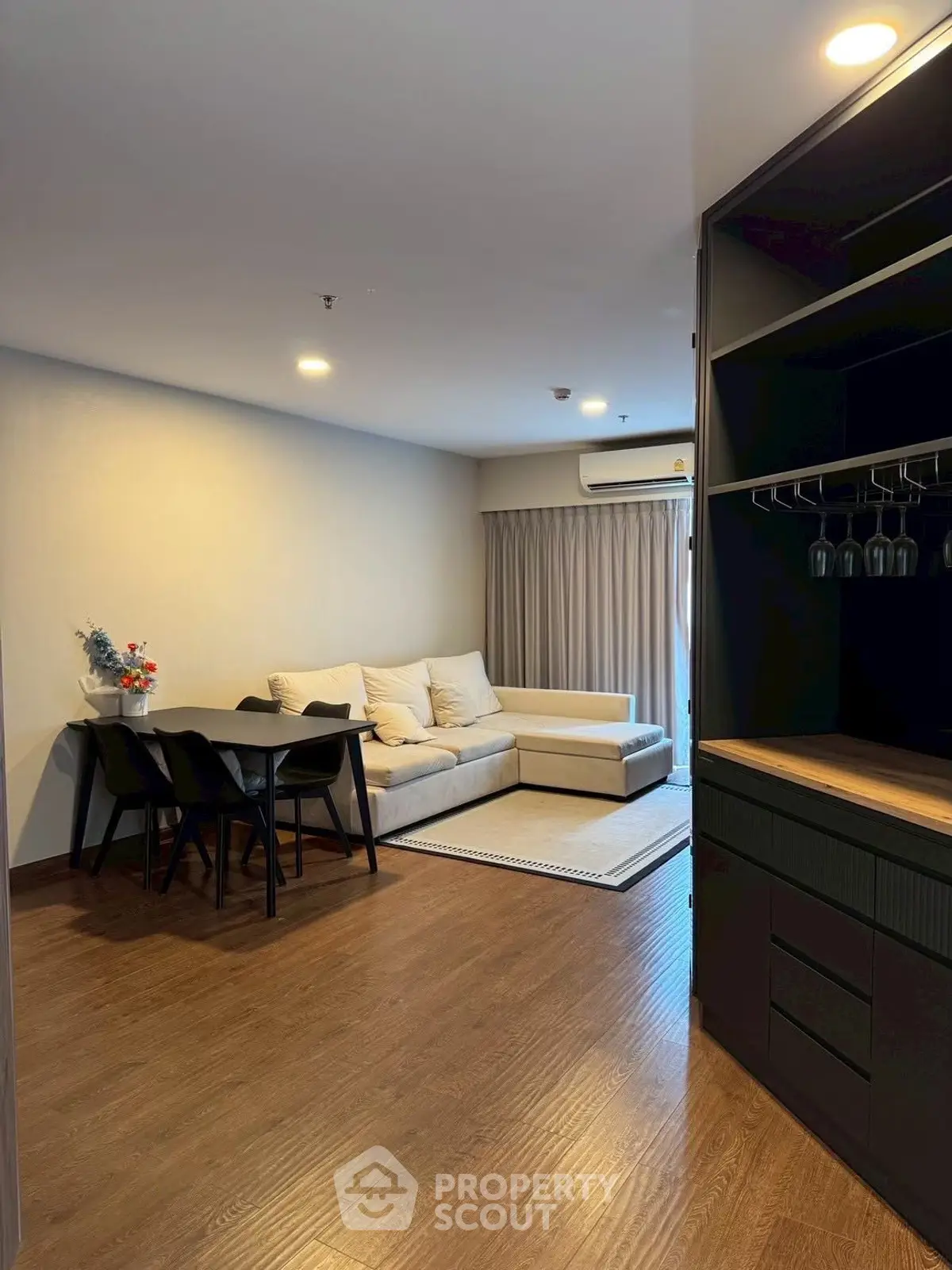 Modern living room with cozy sofa and dining area, featuring elegant wooden flooring and stylish decor.