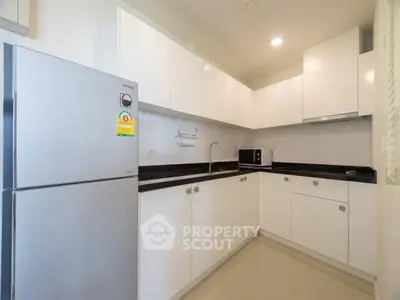 Modern kitchen with sleek white cabinets and stainless steel appliances in a stylish apartment.
