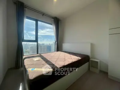 Bright bedroom with large window offering stunning city views in modern apartment.