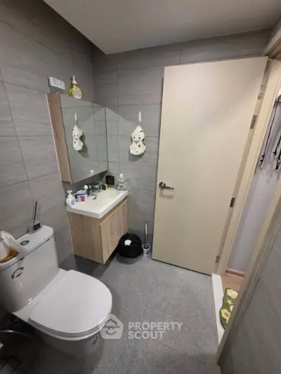 Modern bathroom with sleek fixtures and minimalist design, featuring a compact vanity and neutral tones.