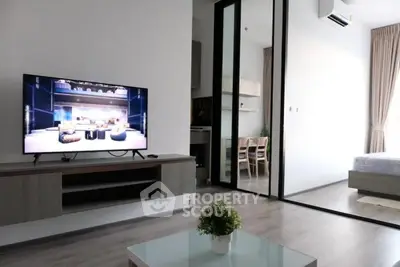 Modern living room with sleek TV setup and glass partition leading to bedroom