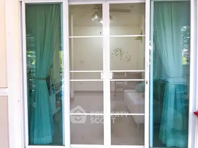 Charming sliding glass doors with teal curtains leading to a cozy interior space.