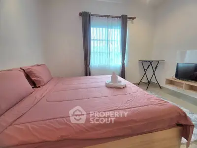 Cozy bedroom with pink bedding and natural light, perfect for relaxation.
