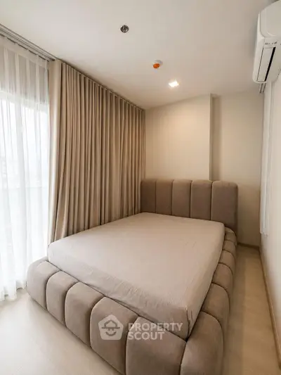 Modern bedroom with plush bed and floor-to-ceiling curtains in a stylish apartment.