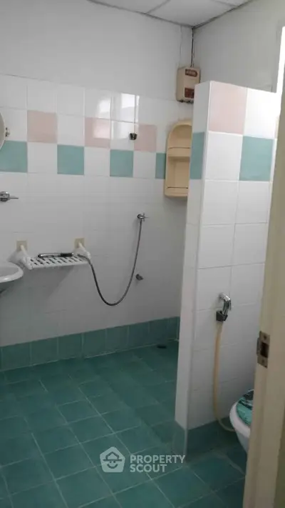 Spacious bathroom with tiled walls and floor, featuring a shower area and modern fixtures.
