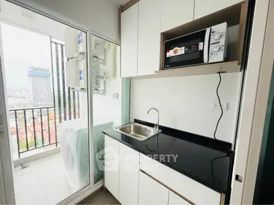 Modern compact kitchen with balcony view in high-rise apartment