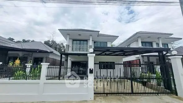 Modern two-story house with gated driveway and contemporary design.