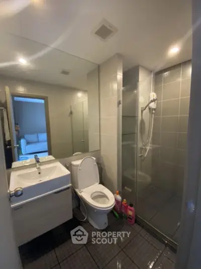 Modern bathroom with glass shower and sleek fixtures in contemporary apartment.