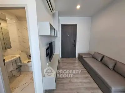 Modern apartment interior with sleek living room and adjacent bathroom, featuring minimalist design and neutral tones.