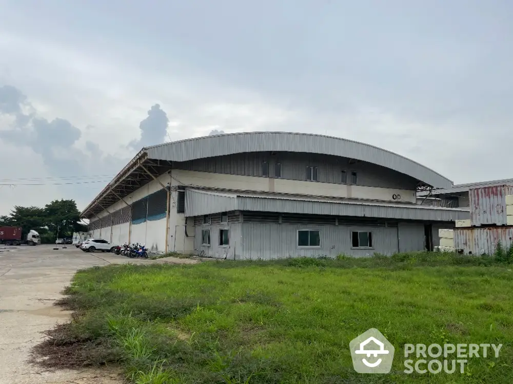 Industrial warehouse exterior with spacious parking and green surroundings