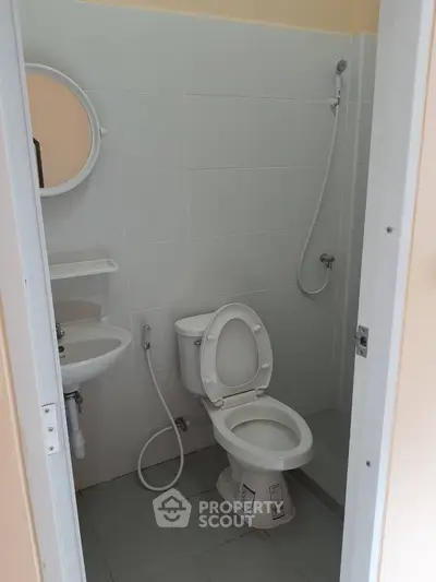 Compact bathroom with shower, toilet, and sink in modern apartment.