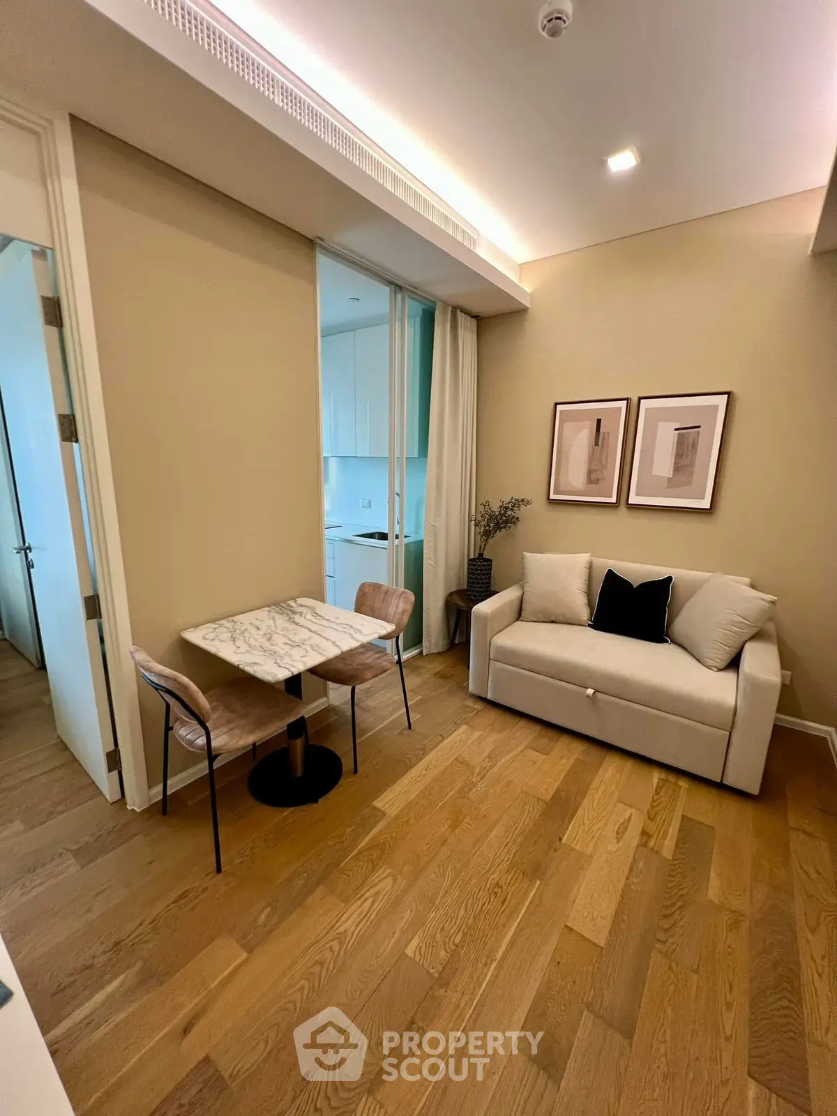 Modern living room with cozy sofa and stylish decor, adjacent to a sleek kitchen area.