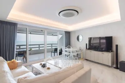 Luxurious living room with ocean view and modern decor, featuring a spacious balcony and elegant furnishings.